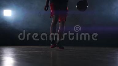 一名青年男子，篮球运动员运球，室内黑暗篮球场